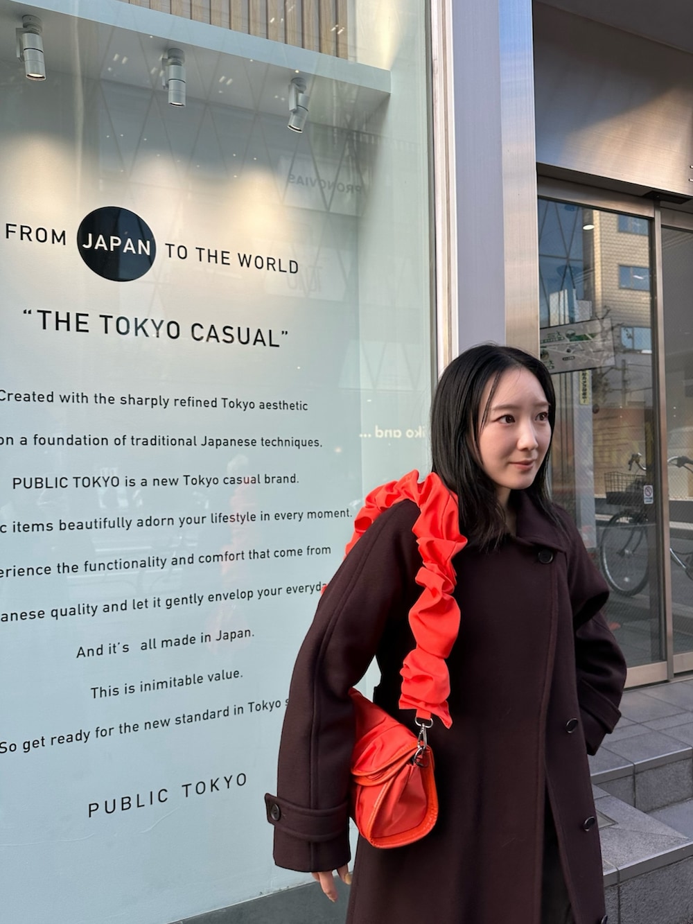 ブラウン系のチェスターコート、オレンジ系のショルダーバッグを着用したレディースの冬コーディネートの5枚目の写真