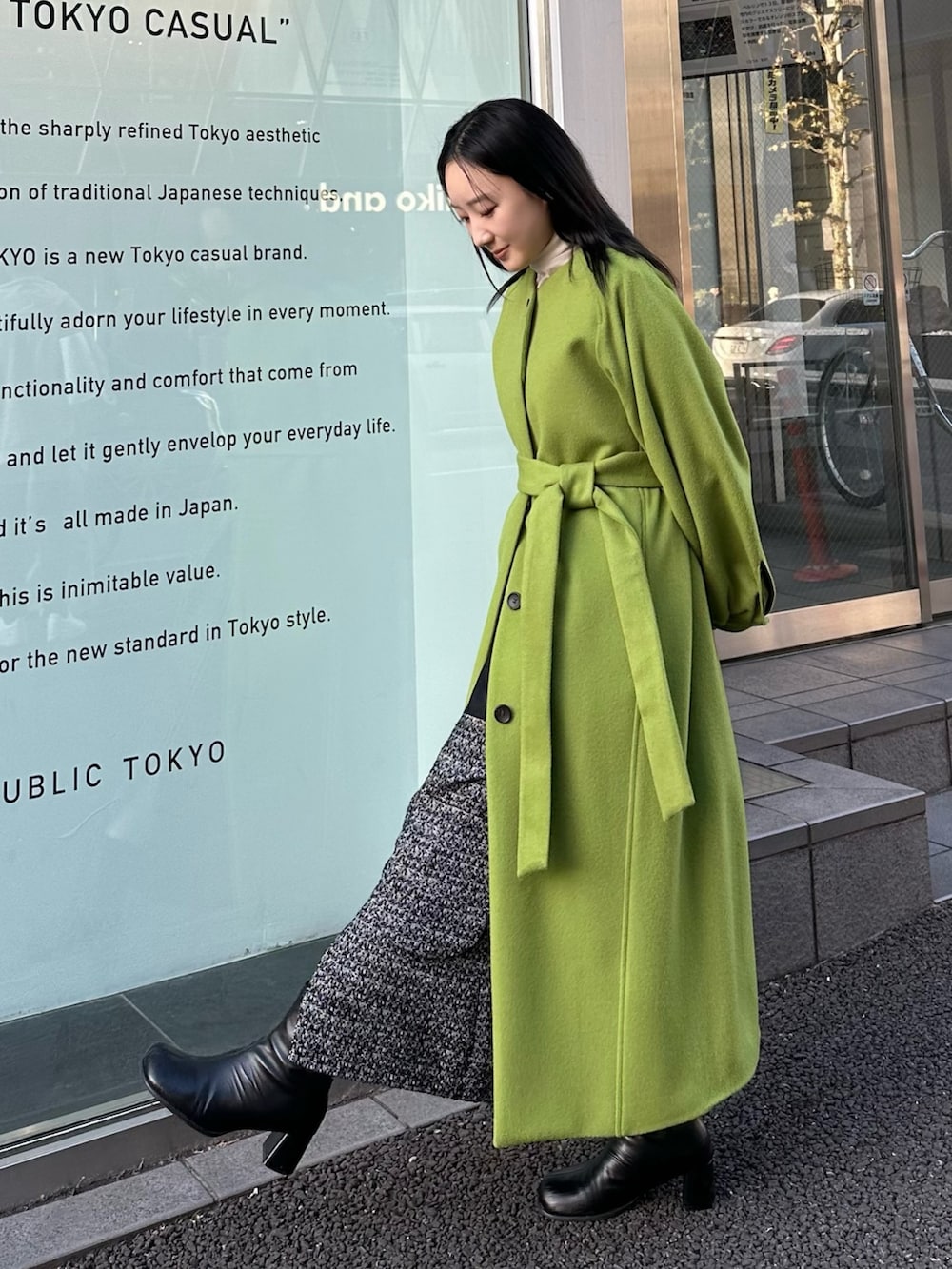 グリーン系のノーカラーコートを着用したレディースの冬コーディネートの2枚目の写真