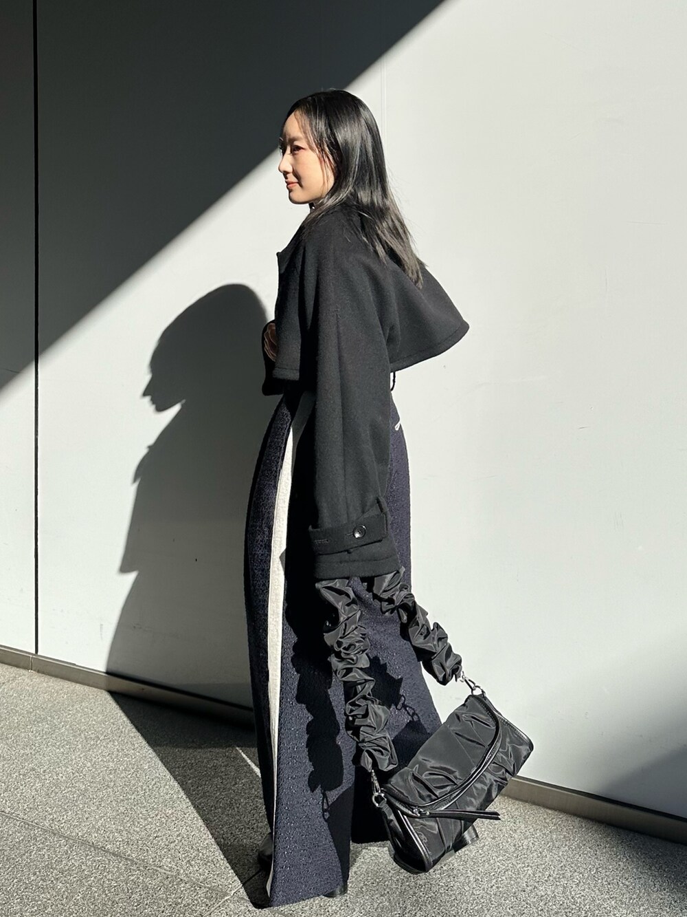 ブルー系のその他パンツ、ブラック系のステンカラーコートを着用したレディースの冬コーディネートの4枚目の写真