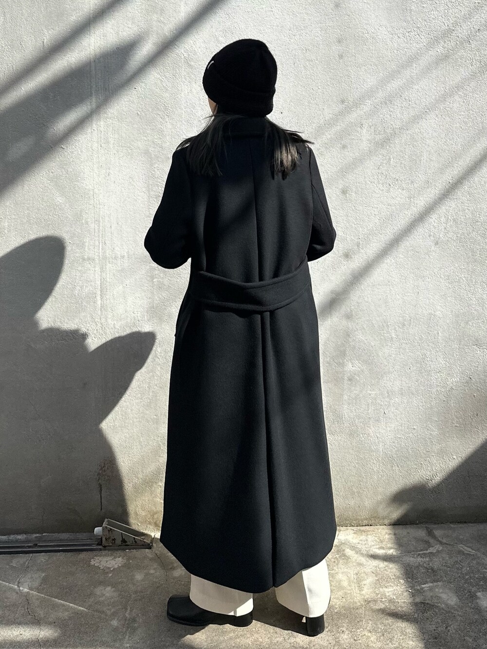 ブラック系のチェスターコートを着用したレディースの秋コーディネートの4枚目の写真