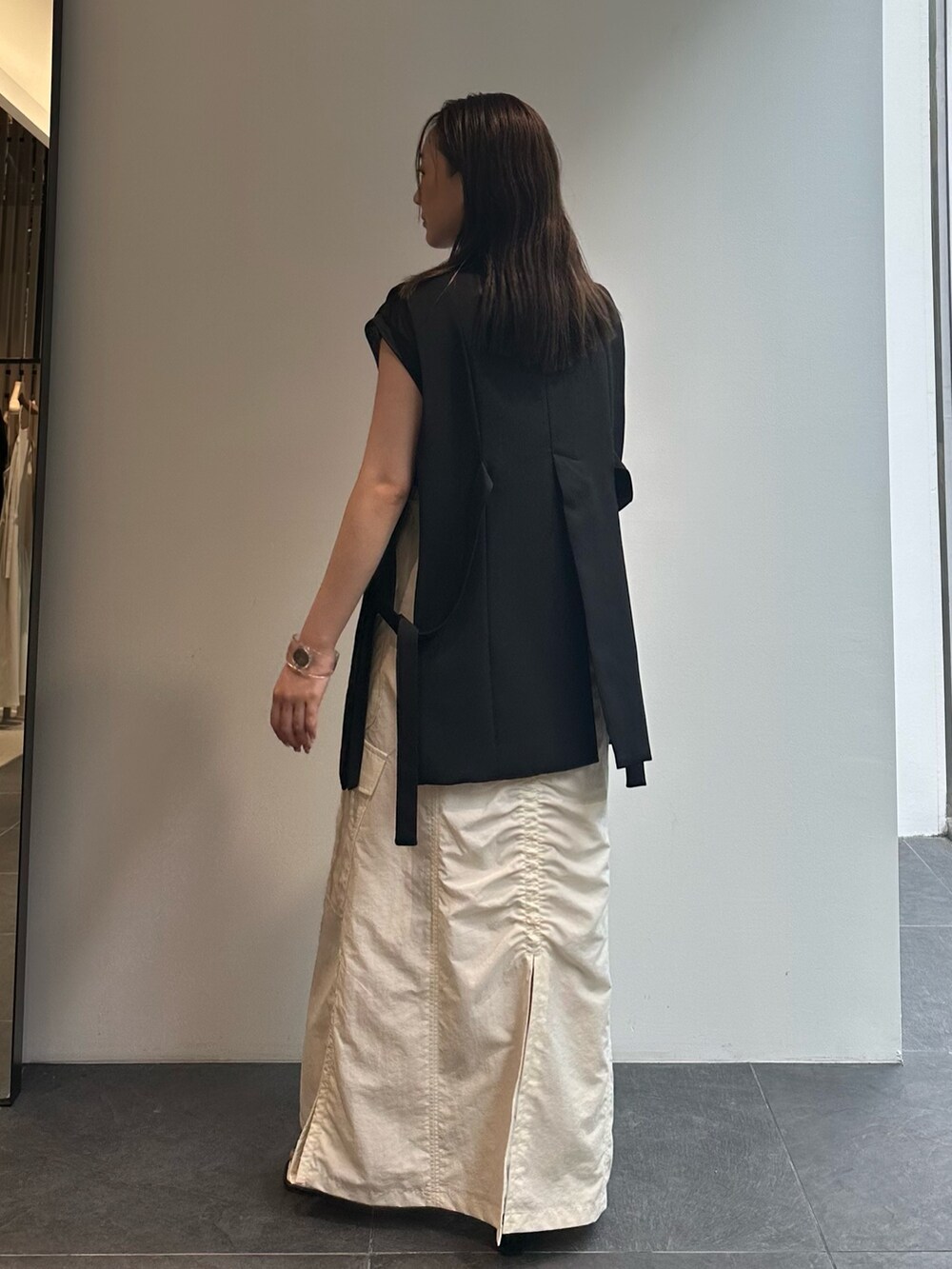 ブラック系のTシャツ/カットソー、ブラック系のベスト、ホワイト系のスカートを着用したレディースの夏コーディネートの5枚目の写真