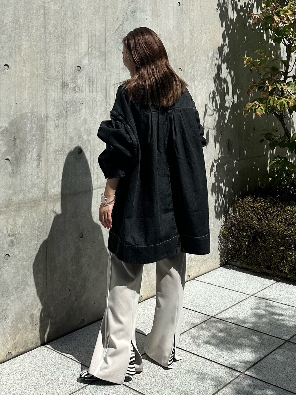 ホワイト系のスラックス、ブラック系のデニムジャケットを着用したレディースの夏コーディネートの3枚目の写真