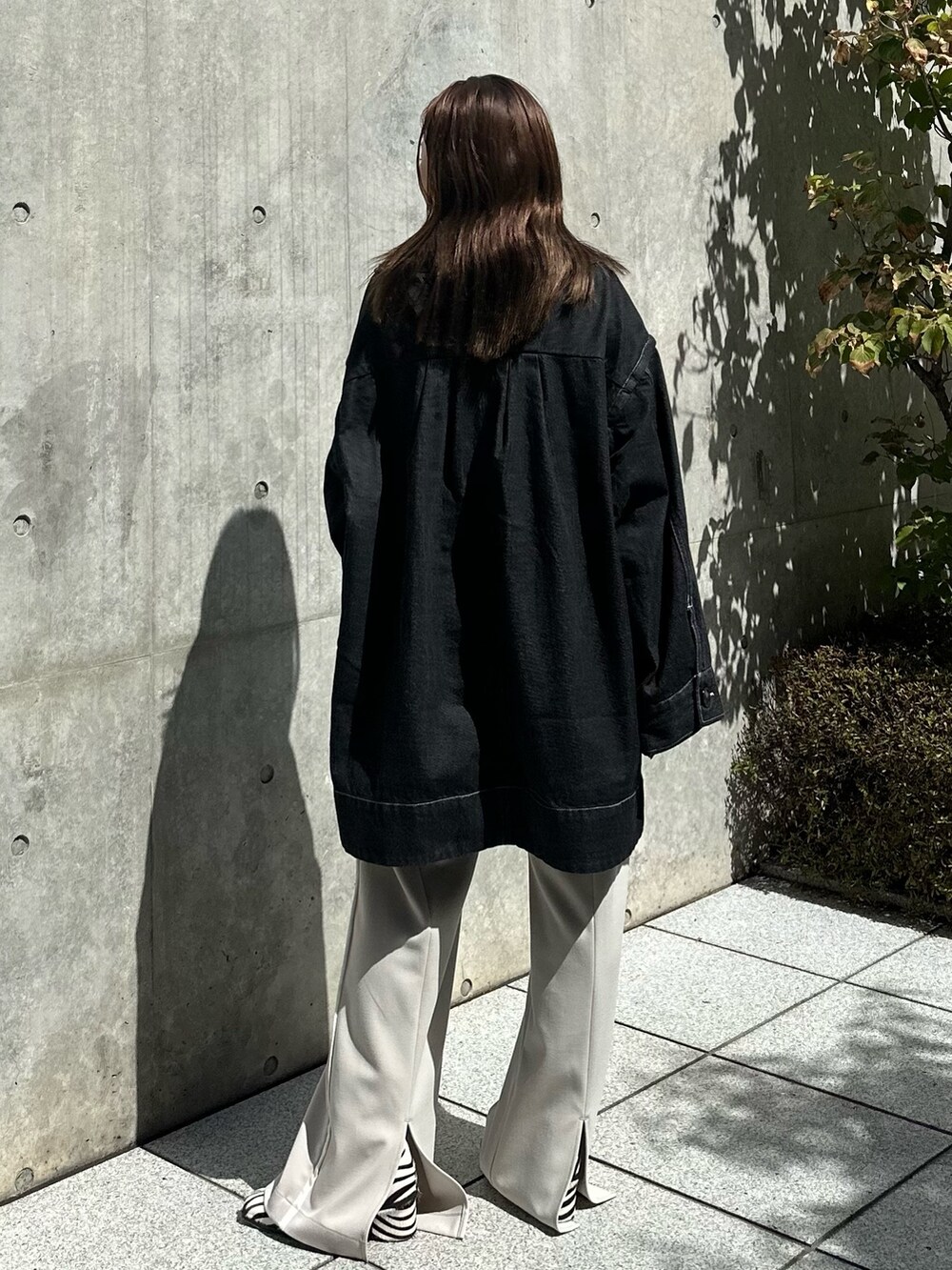 ホワイト系のスラックス、ブラック系のデニムジャケットを着用したレディースの夏コーディネートの4枚目の写真