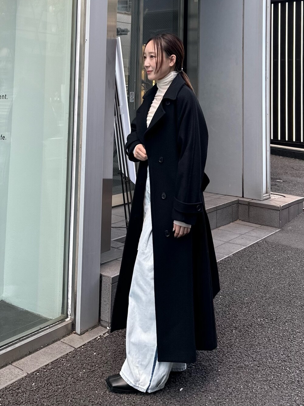 ブラック系のチェスターコートを着用したレディースの秋コーディネートの2枚目の写真