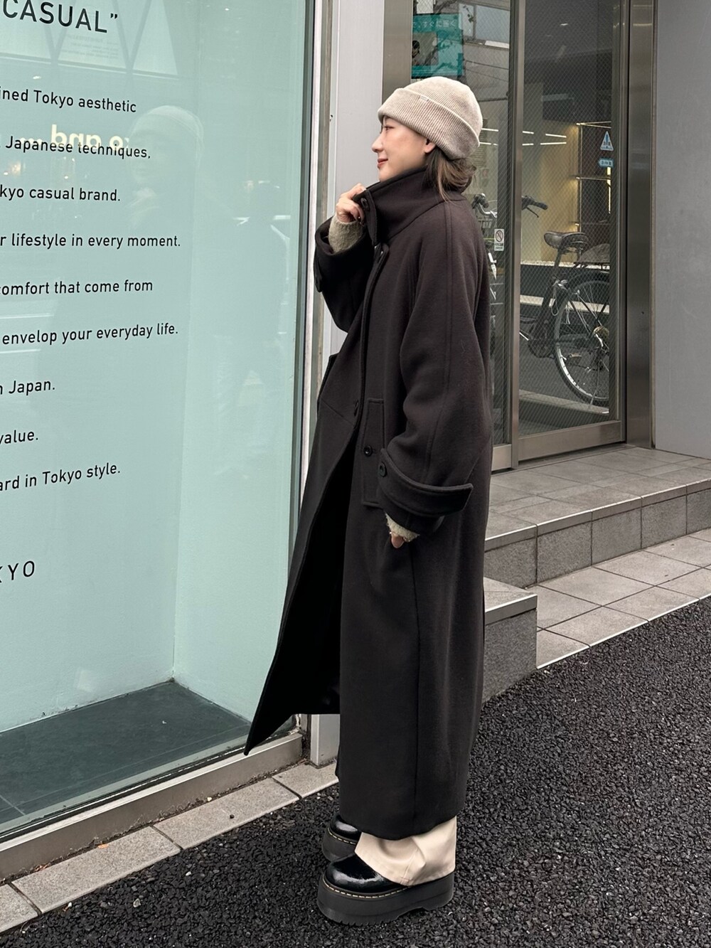 グレー系のステンカラーコートを着用したレディースの秋コーディネートの3枚目の写真