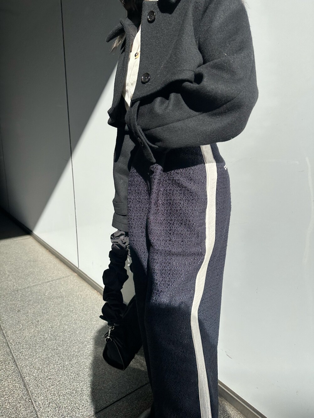 ブルー系のその他パンツ、ブラック系のステンカラーコートを着用したレディースの冬コーディネートの5枚目の写真