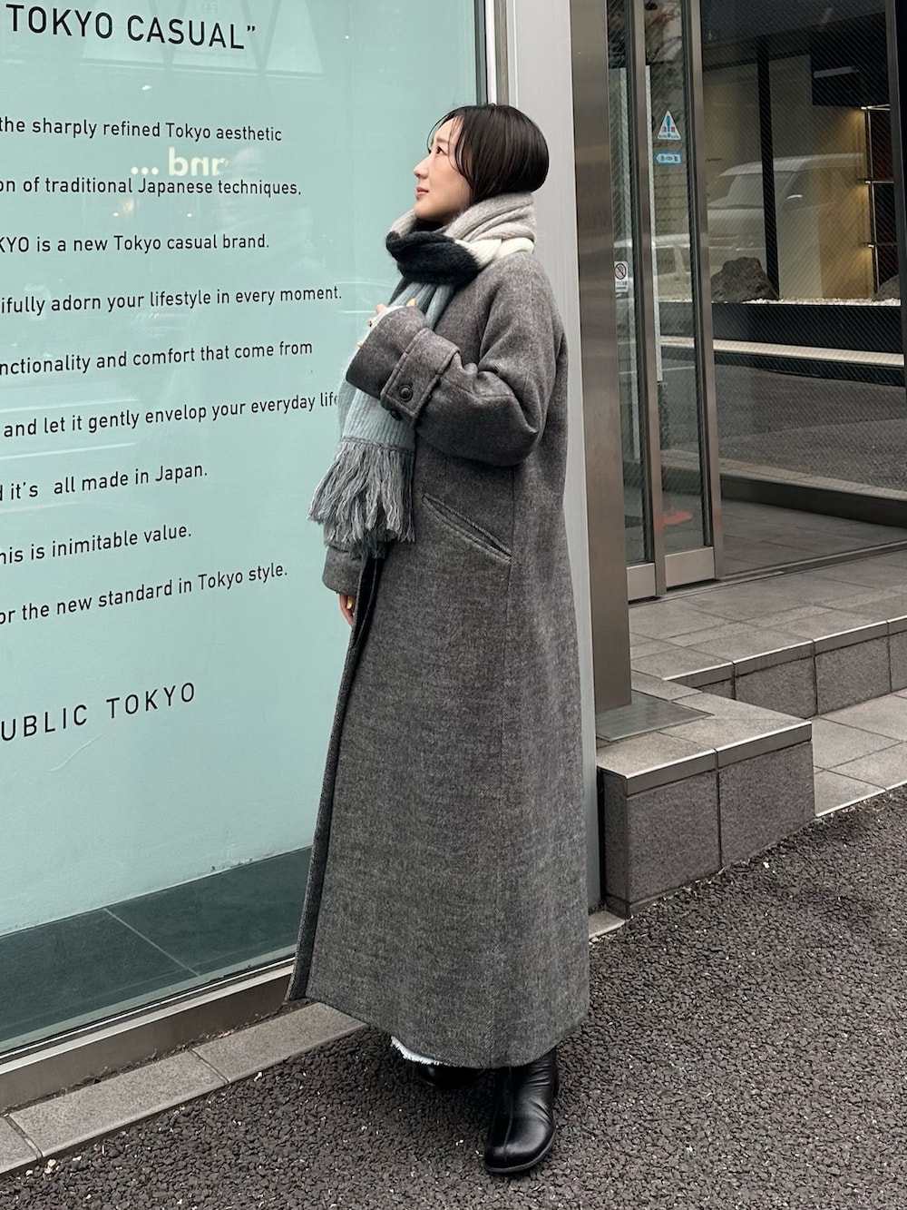 ブルー系のステンカラーコート、グレー系のマフラーを着用したレディースの冬コーディネートの2枚目の写真
