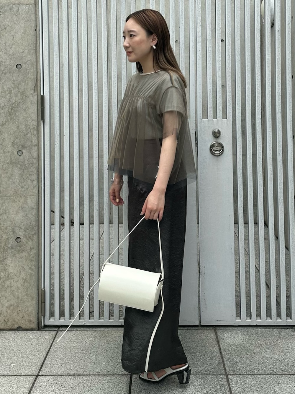 ブラック系のスカート、ベージュ系のシャツ/ブラウス、グリーン系のTシャツ/カットソーを着用したレディースの夏コーディネートの4枚目の写真