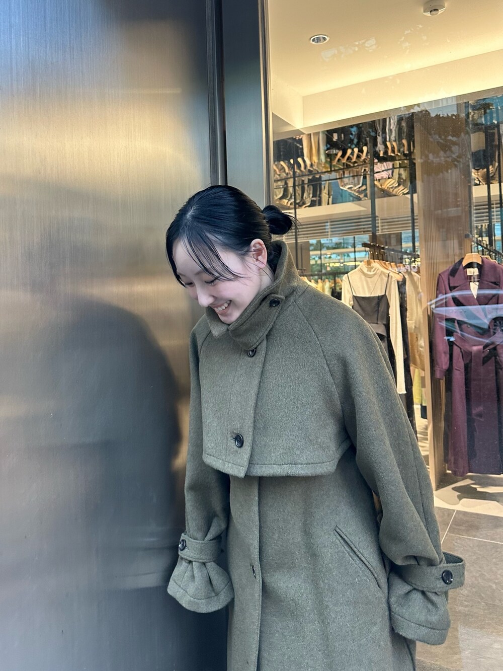 グリーン系のステンカラーコートを着用したレディースの秋コーディネートの5枚目の写真