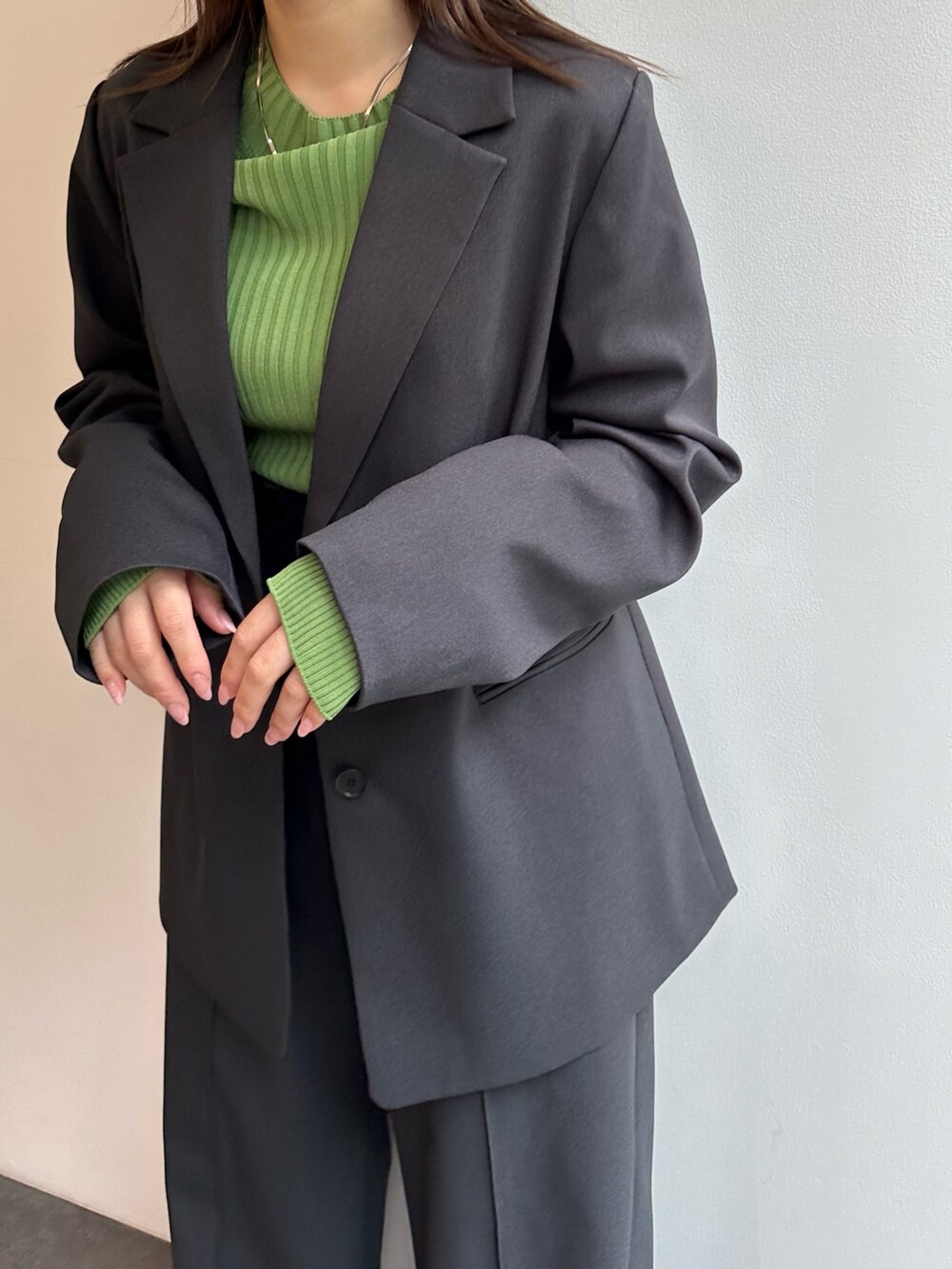 グリーン系のニット/セーター、グレー系のスラックス、グレー系のテーラードジャケットを着用したレディースの秋コーディネートの5枚目の写真
