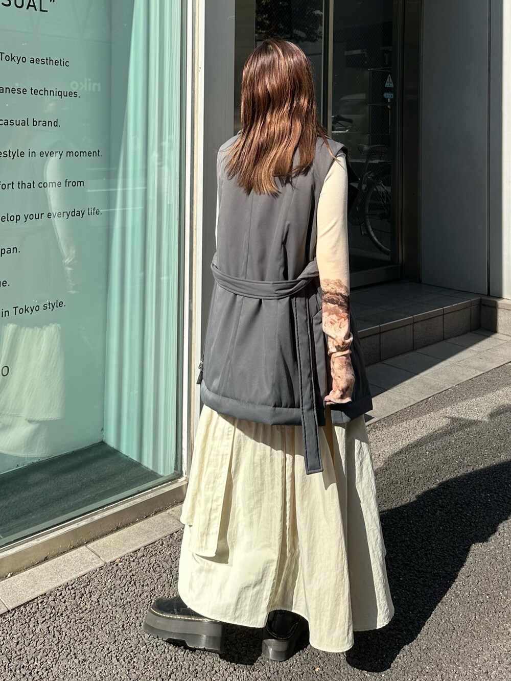 ベージュ系のスカート、ブラック系のダウンベスト、ブルー系のTシャツ/カットソーを着用したレディースの秋コーディネートの3枚目の写真