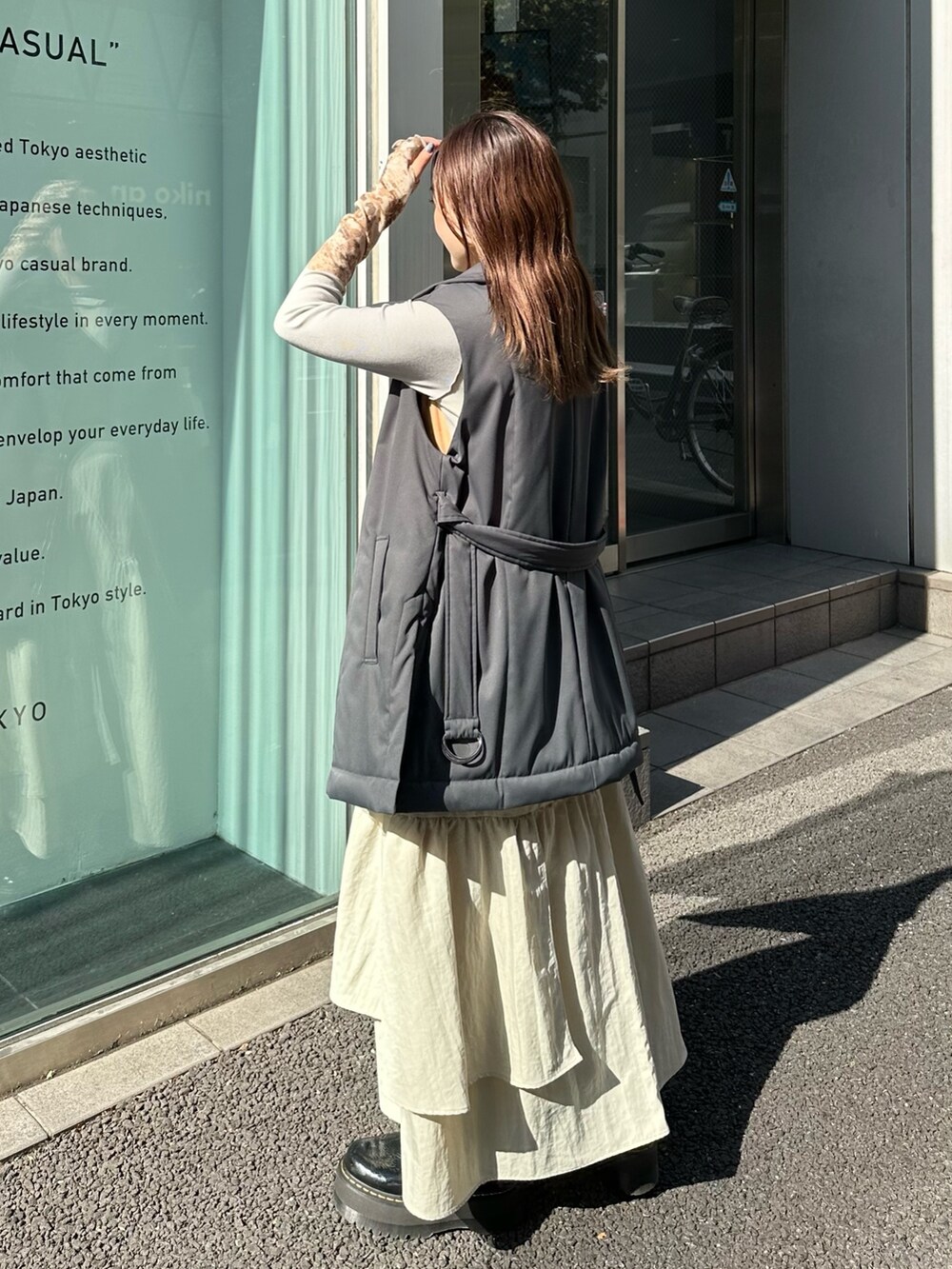 ベージュ系のスカート、ブラック系のダウンベスト、ブルー系のTシャツ/カットソーを着用したレディースの秋コーディネートの4枚目の写真