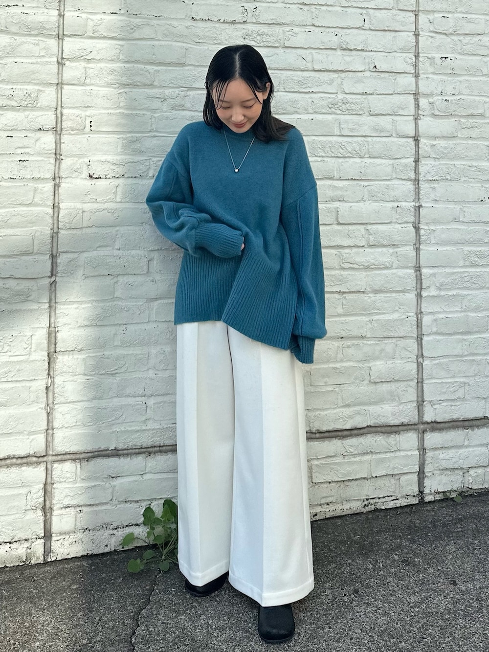 ベージュ系のスラックス、ブルー系のニット/セーターを着用したレディースの秋コーディネートの2枚目の写真