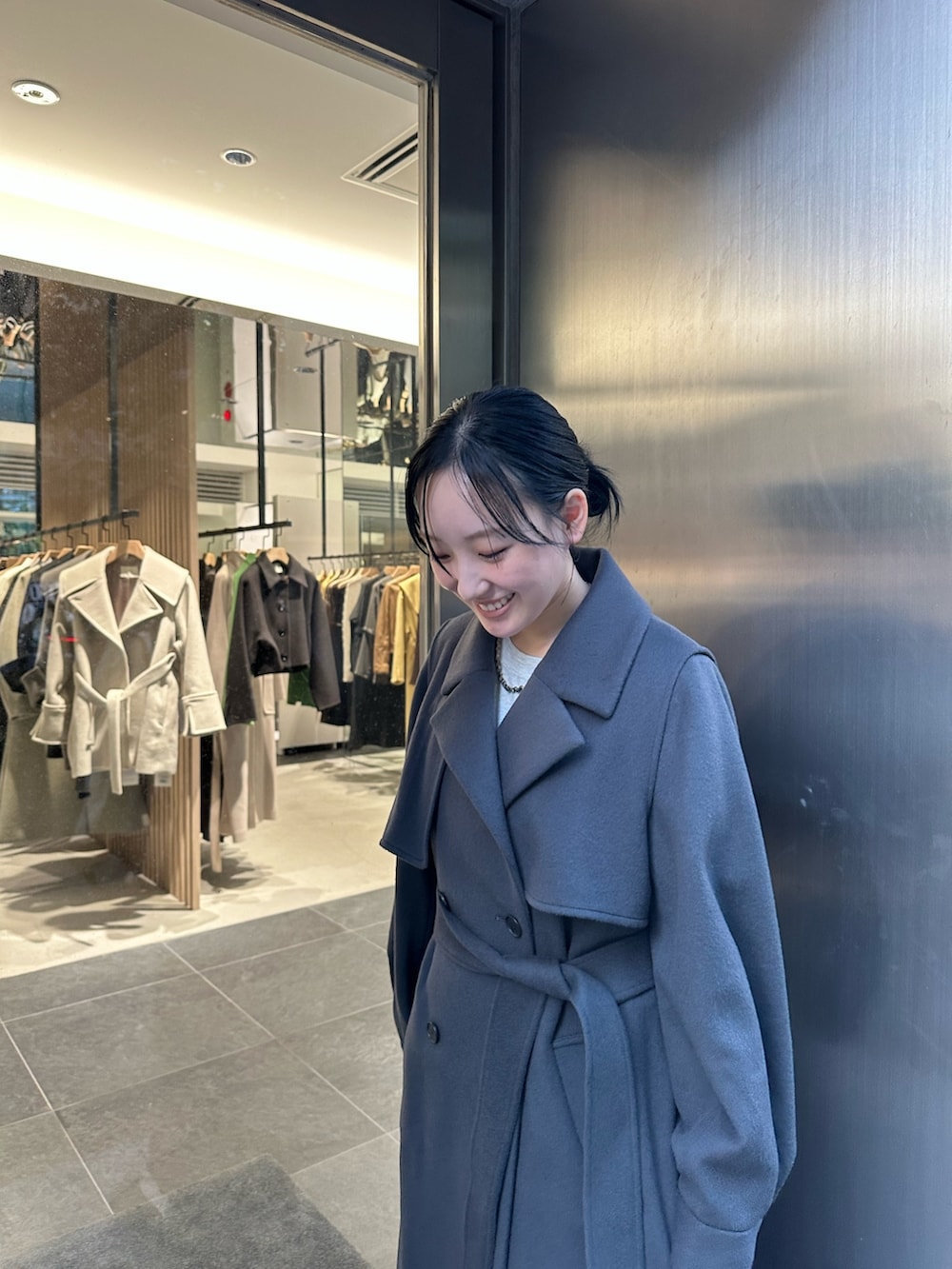 グレー系のステンカラーコートを着用したレディースの秋コーディネートの5枚目の写真