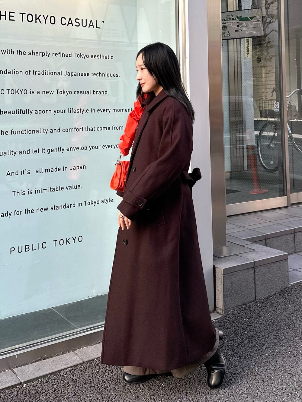 ブラウン系のチェスターコート、オレンジ系のショルダーバッグを着用したレディースの冬コーディネートの2枚目の写真