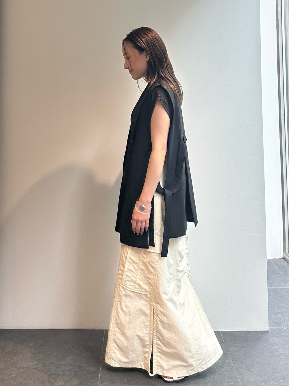ブラック系のTシャツ/カットソー、ブラック系のベスト、ホワイト系のスカートを着用したレディースの夏コーディネートの3枚目の写真