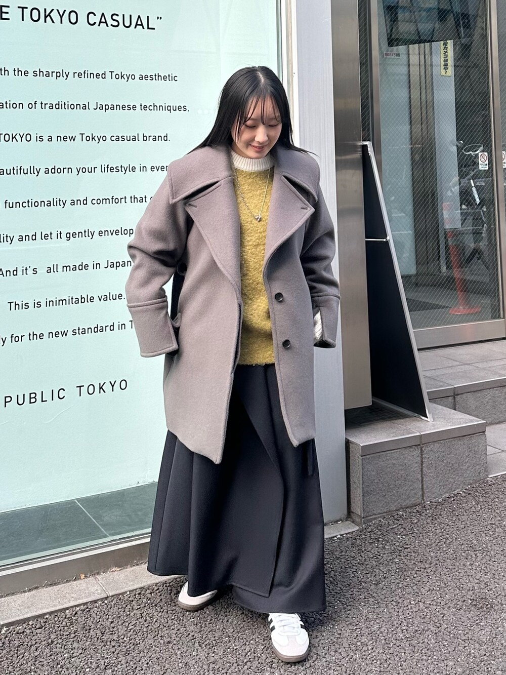 グレー系のチェスターコート、ブラック系のスカートを着用したレディースの冬コーディネートの2枚目の写真