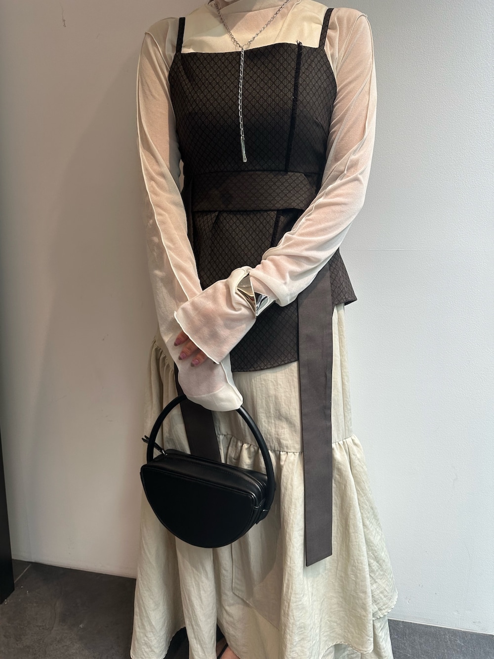 ホワイト系のTシャツ/カットソー、ブラウン系のキャミソール、ベージュ系のスカートを着用したレディースの秋コーディネートの5枚目の写真