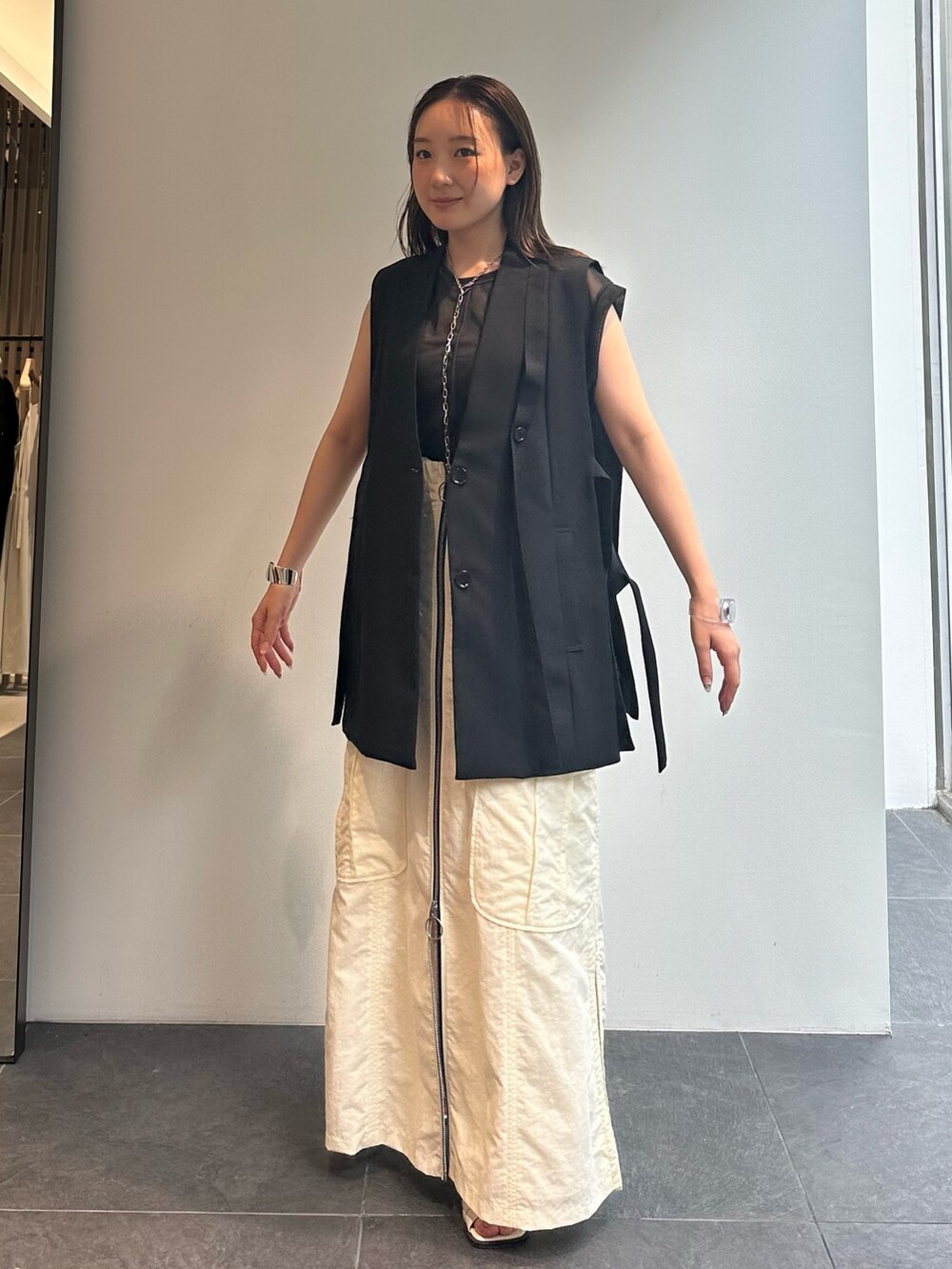 ブラック系のTシャツ/カットソー、ブラック系のベスト、ホワイト系のスカートを着用したレディースの夏コーディネートの2枚目の写真