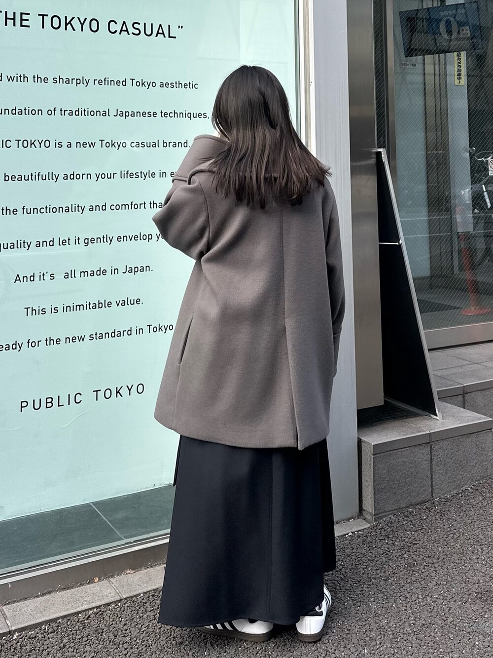 グレー系のチェスターコート、ブラック系のスカートを着用したレディースの冬コーディネートの3枚目の写真