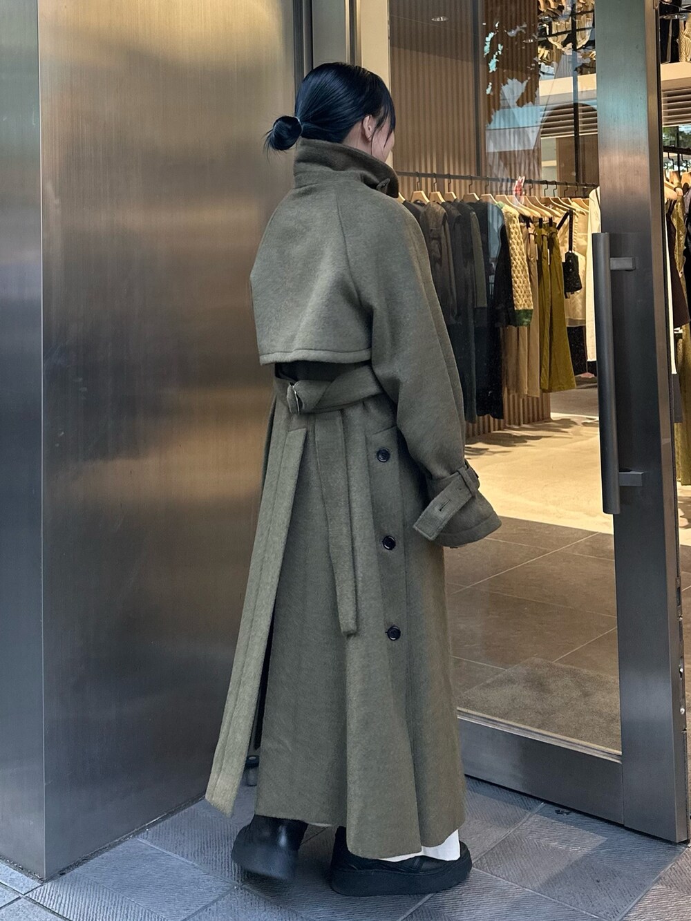 グリーン系のステンカラーコートを着用したレディースの秋コーディネートの3枚目の写真