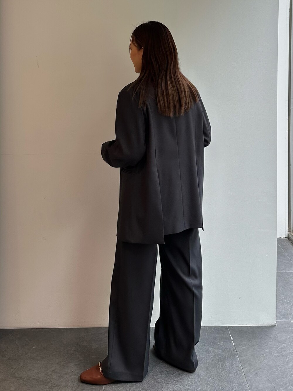 グリーン系のニット/セーター、グレー系のスラックス、グレー系のテーラードジャケットを着用したレディースの秋コーディネートの3枚目の写真