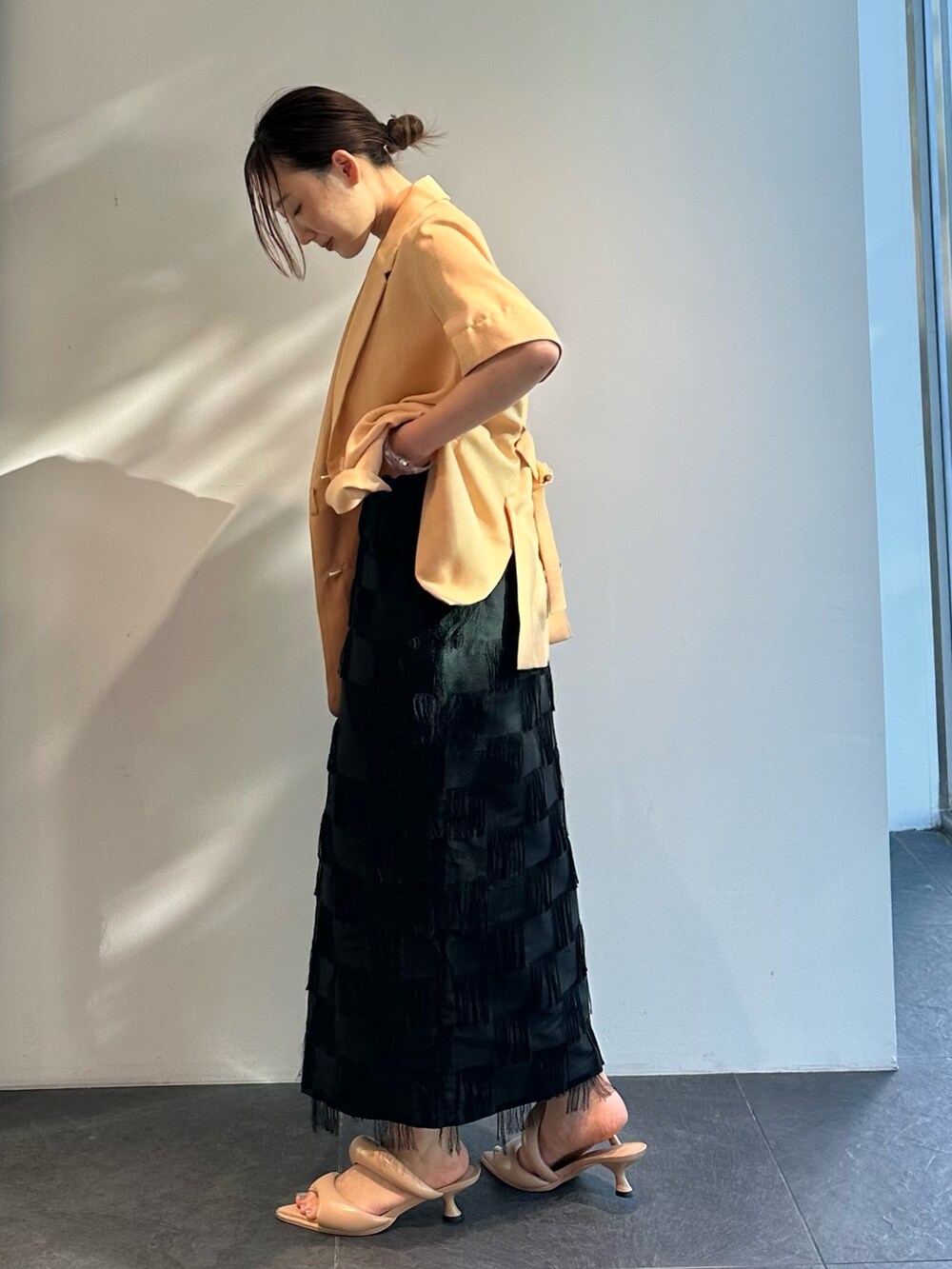 オレンジ系のシャツ/ブラウス、ブラック系のスカートを着用したレディースの夏コーディネートの4枚目の写真