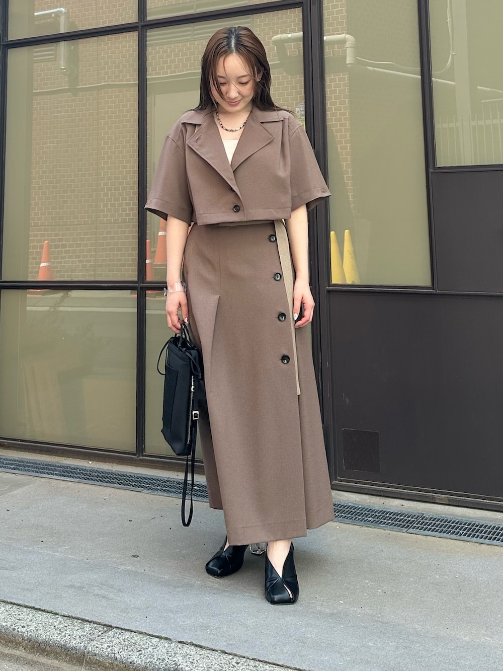 ベージュ系のシャツ/ブラウス、ベージュ系のスカート、ブラック系のハンドバッグを着用したレディースの春コーディネートの2枚目の写真