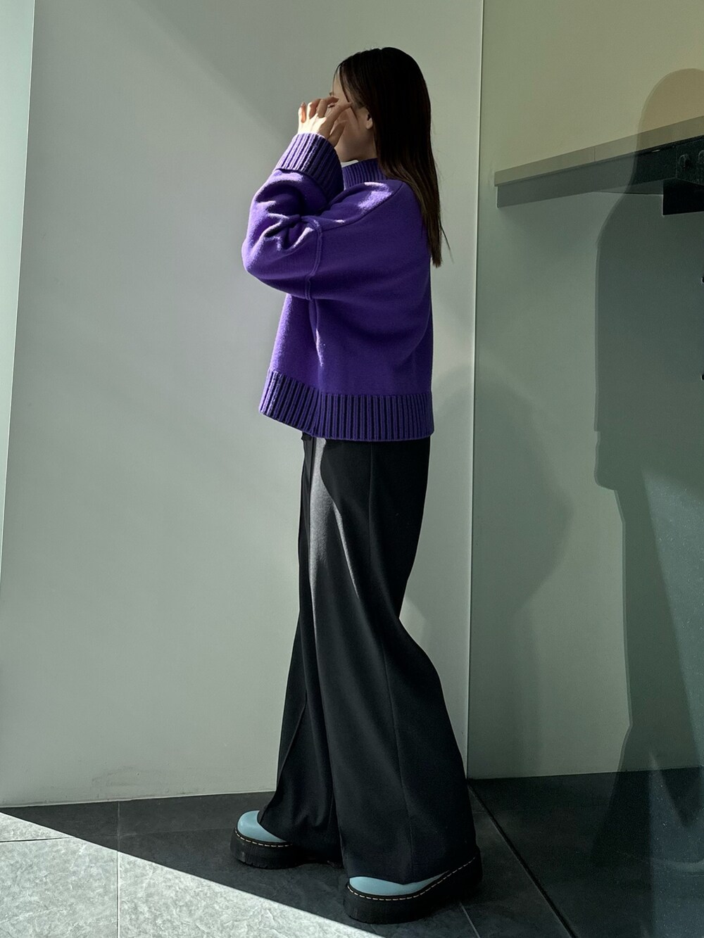 パープル系のニット/セーター、グレー系のスラックスを着用したレディースの秋コーディネートの3枚目の写真