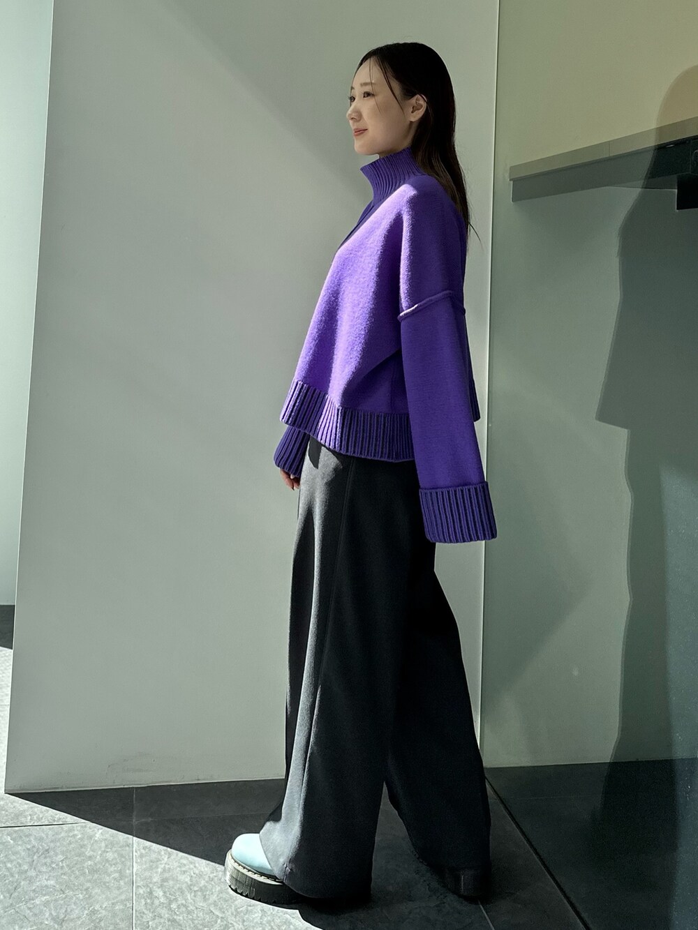パープル系のニット/セーター、グレー系のスラックスを着用したレディースの秋コーディネートの4枚目の写真
