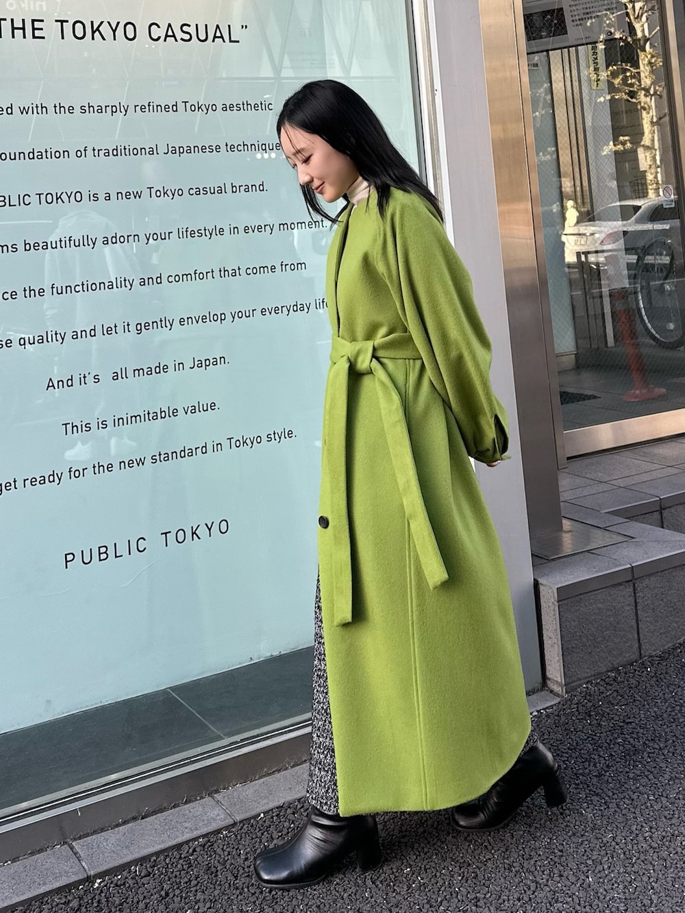 グリーン系のノーカラーコートを着用したレディースの冬コーディネートの3枚目の写真