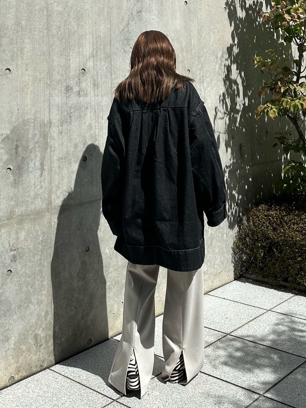 ホワイト系のスラックス、ブラック系のデニムジャケットを着用したレディースの夏コーディネートの5枚目の写真