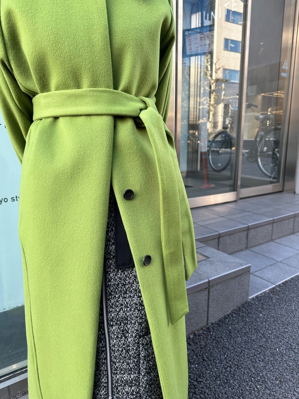 グリーン系のノーカラーコートを着用したレディースの冬コーディネートの5枚目の写真