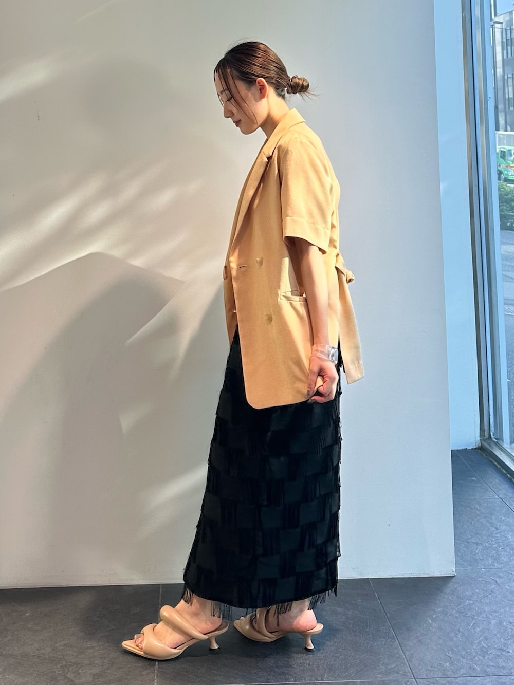 オレンジ系のシャツ/ブラウス、ブラック系のスカートを着用したレディースの夏コーディネートの3枚目の写真