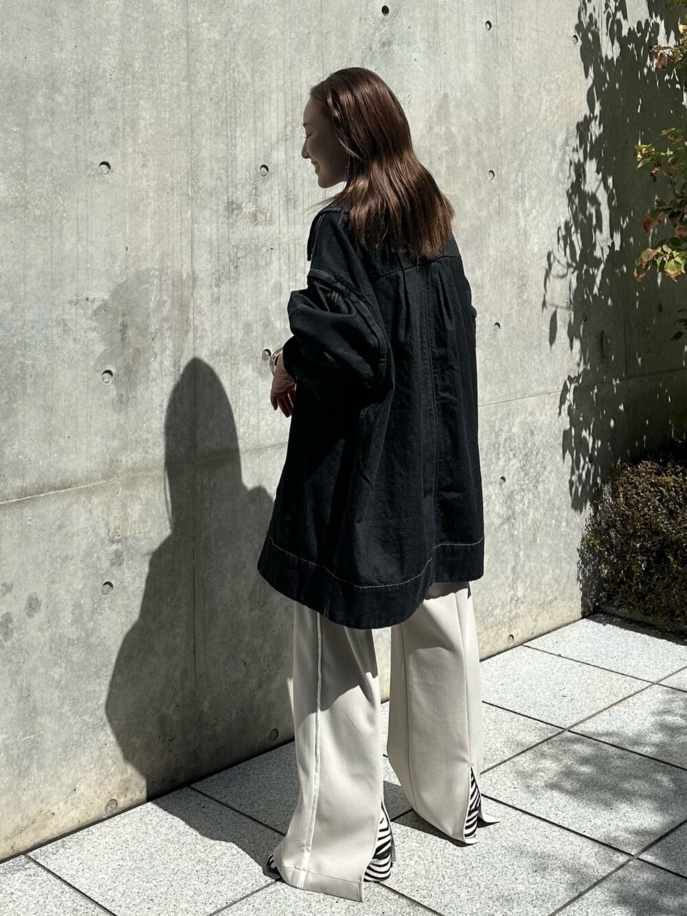 ホワイト系のスラックス、ブラック系のデニムジャケットを着用したレディースの夏コーディネートの2枚目の写真