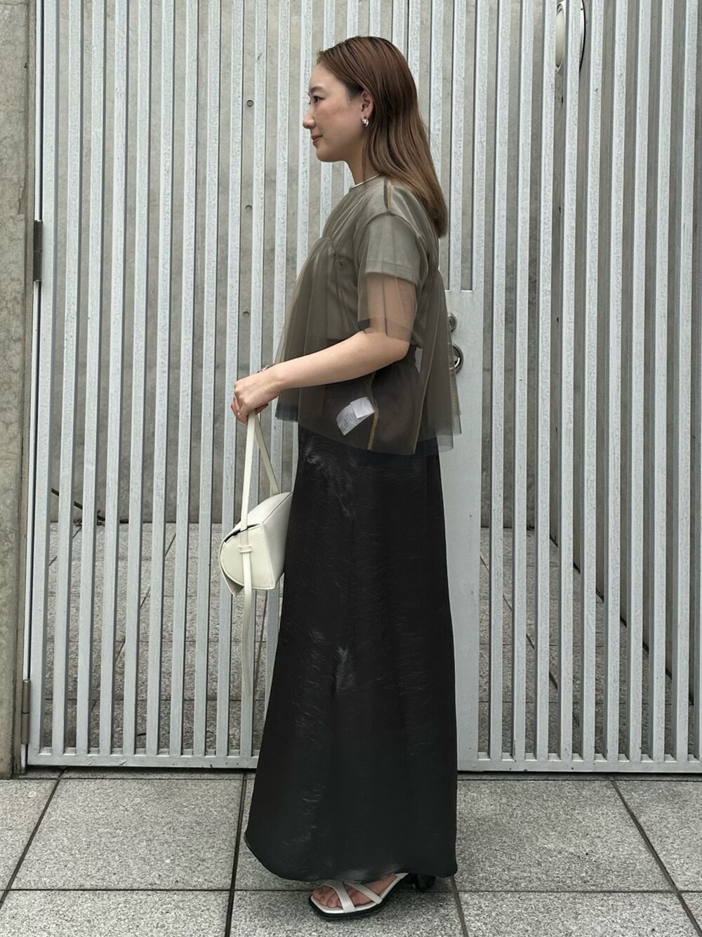 ブラック系のスカート、ベージュ系のシャツ/ブラウス、グリーン系のTシャツ/カットソーを着用したレディースの夏コーディネートの3枚目の写真