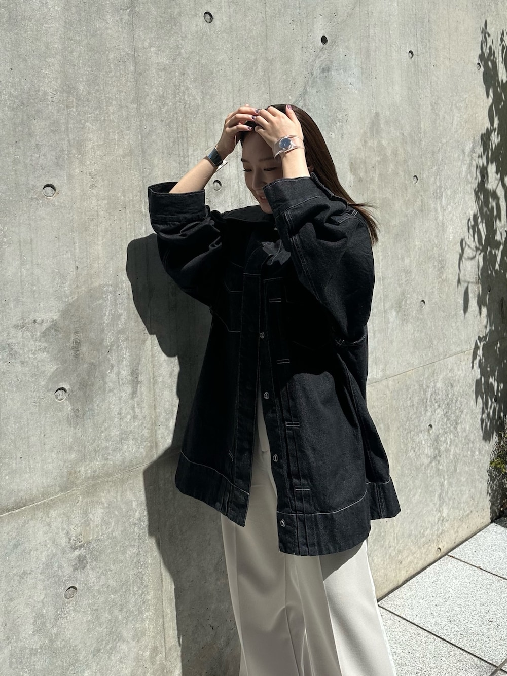 ホワイト系のスラックス、ブラック系のデニムジャケットを着用したレディースの夏コーディネートの6枚目の写真