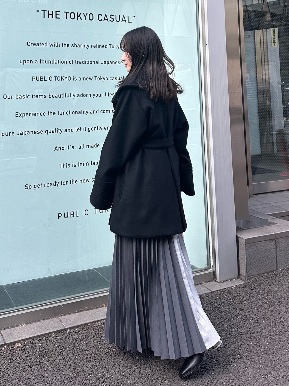 ブラック系のチェスターコート、グレー系のスカートを着用したレディースの冬コーディネートの2枚目の写真