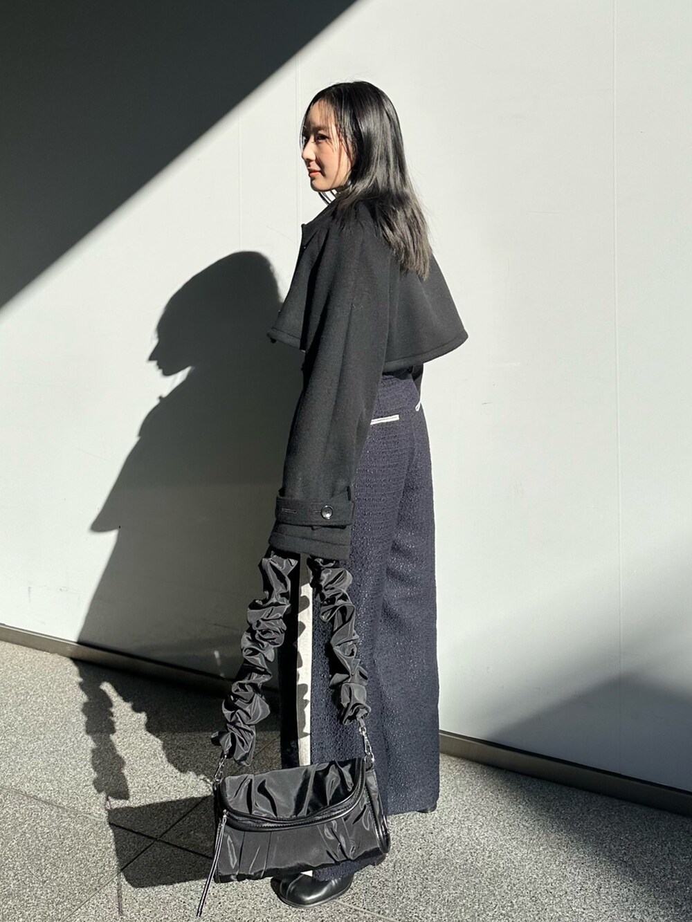 ブルー系のその他パンツ、ブラック系のステンカラーコートを着用したレディースの冬コーディネートの2枚目の写真