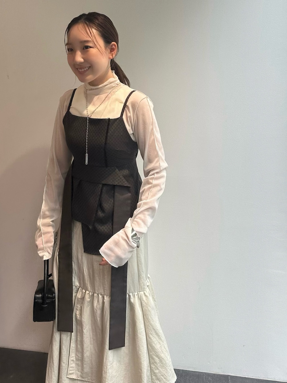 ホワイト系のTシャツ/カットソー、ブラウン系のキャミソール、ベージュ系のスカートを着用したレディースの秋コーディネートの6枚目の写真