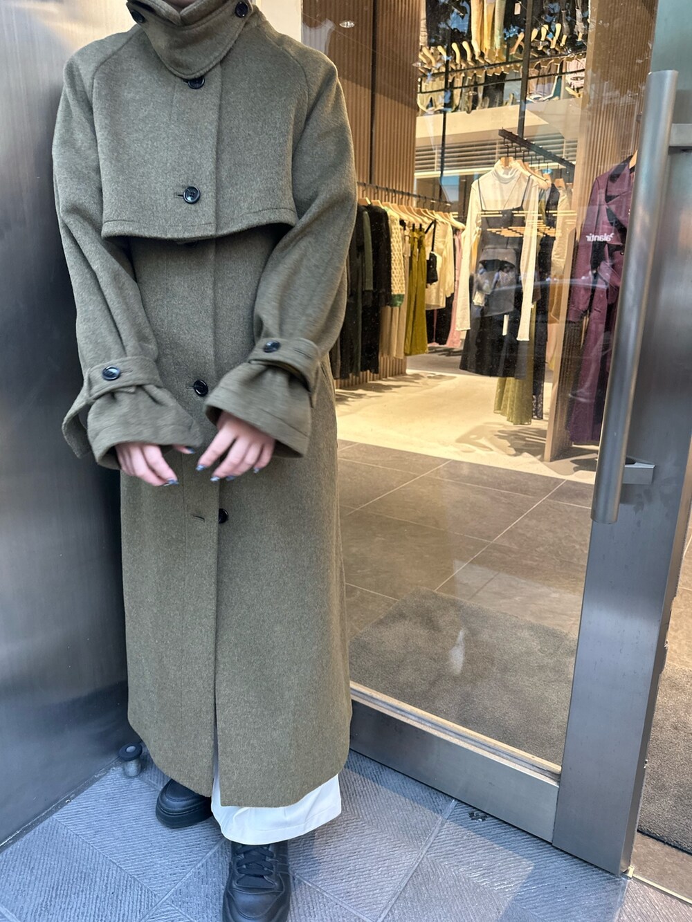 グリーン系のステンカラーコートを着用したレディースの秋コーディネートの4枚目の写真