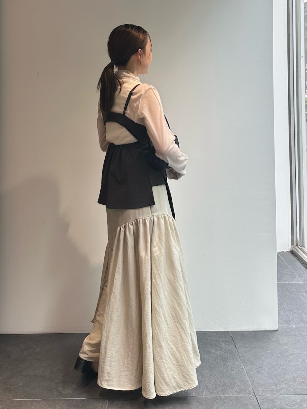 ホワイト系のTシャツ/カットソー、ブラウン系のキャミソール、ベージュ系のスカートを着用したレディースの秋コーディネートの4枚目の写真