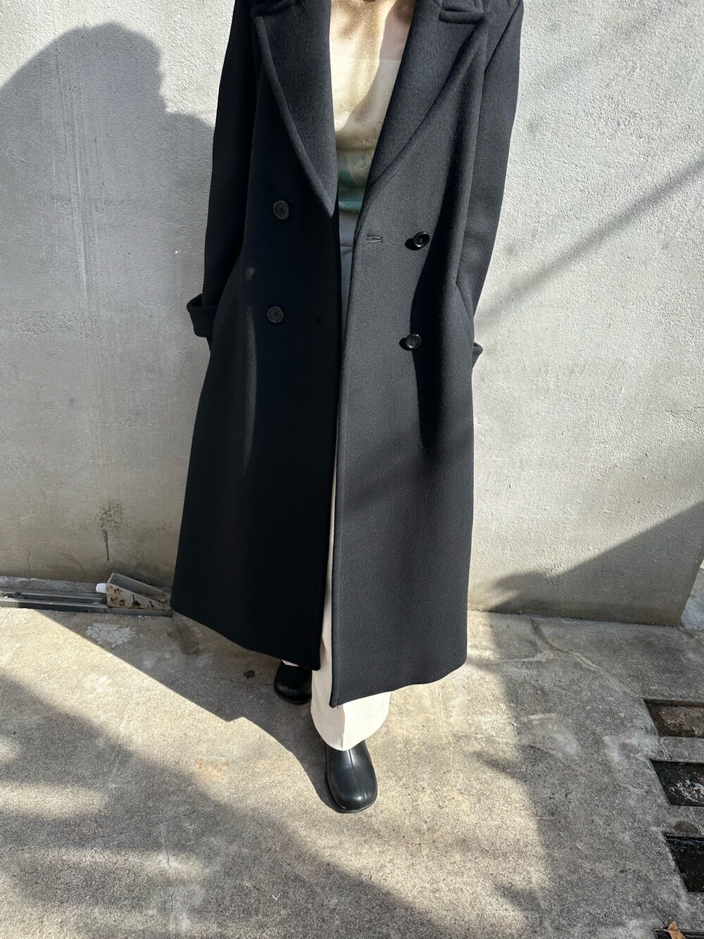 ブラック系のチェスターコートを着用したレディースの秋コーディネートの6枚目の写真