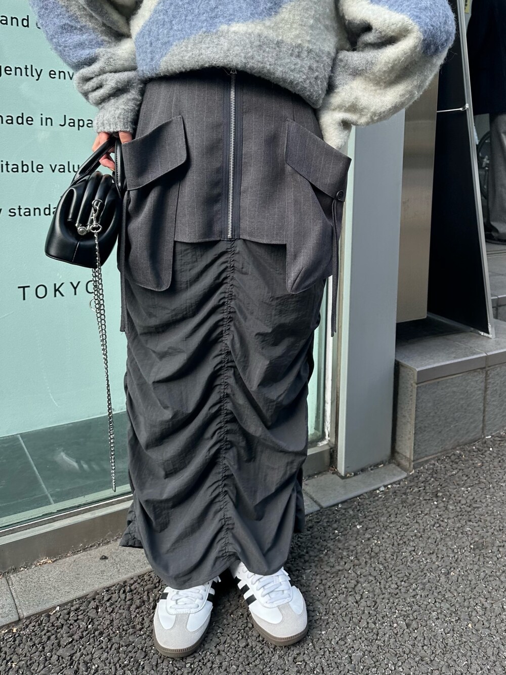 グレー系のスカート、グレー系のニット/セーター、ブラック系のハンドバッグを着用したレディースの冬コーディネートの5枚目の写真