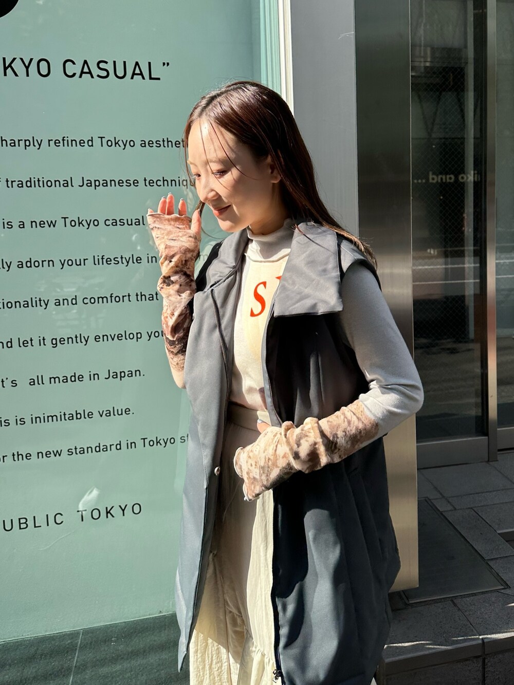 ベージュ系のスカート、ブラック系のダウンベスト、ブルー系のTシャツ/カットソーを着用したレディースの秋コーディネートの5枚目の写真