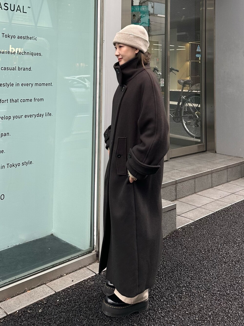 グレー系のステンカラーコートを着用したレディースの秋コーディネートの2枚目の写真