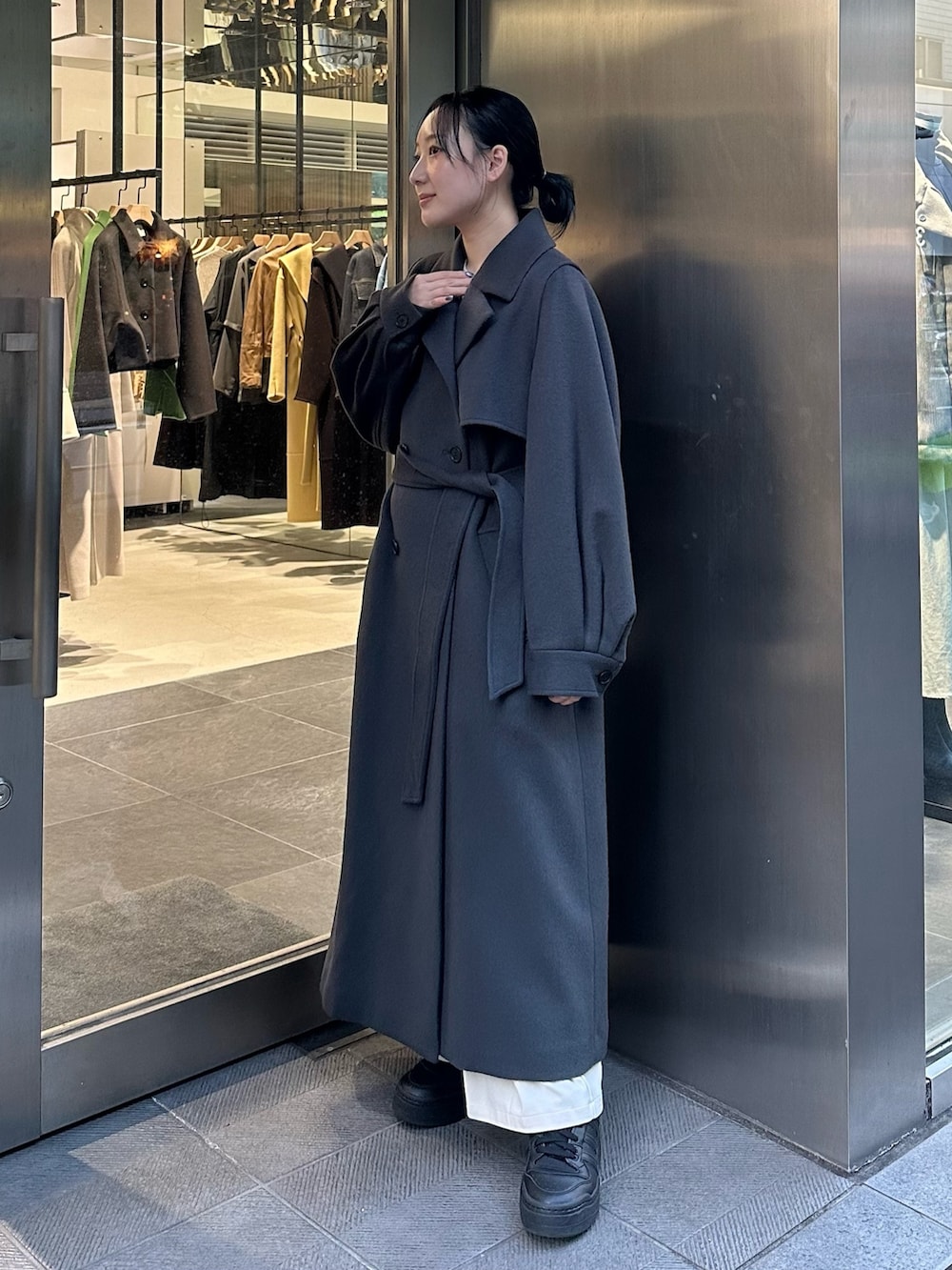 グレー系のステンカラーコートを着用したレディースの秋コーディネートの2枚目の写真