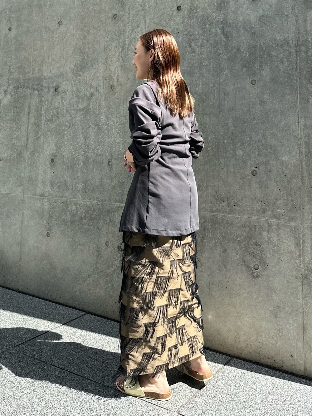 ブラウン系のスカート、グレー系のTシャツ/カットソーを着用したレディースの夏コーディネートの2枚目の写真