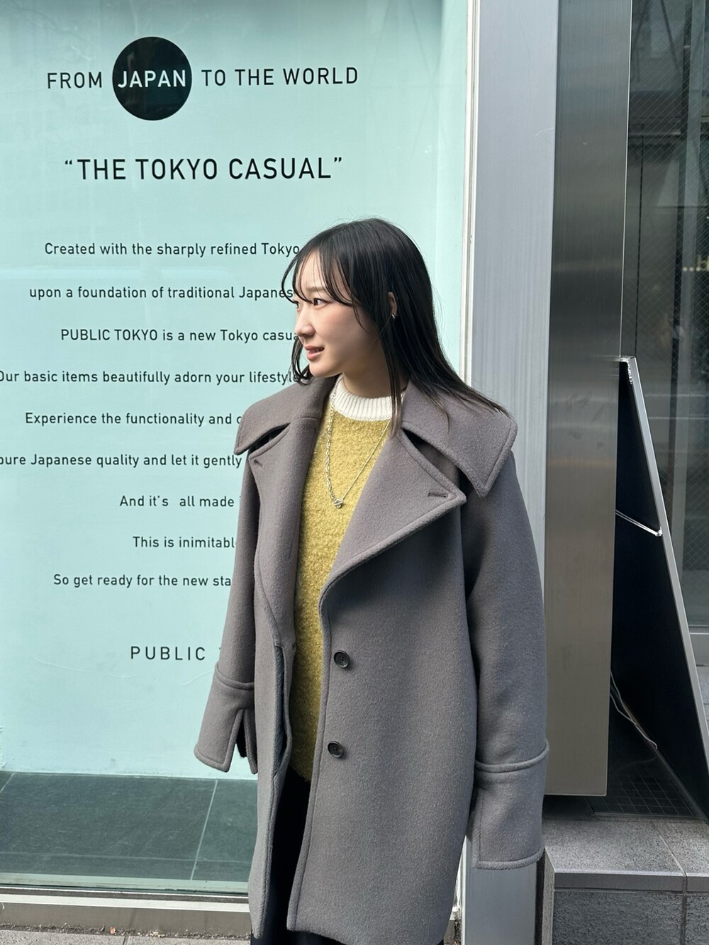 グレー系のチェスターコート、ブラック系のスカートを着用したレディースの冬コーディネートの5枚目の写真