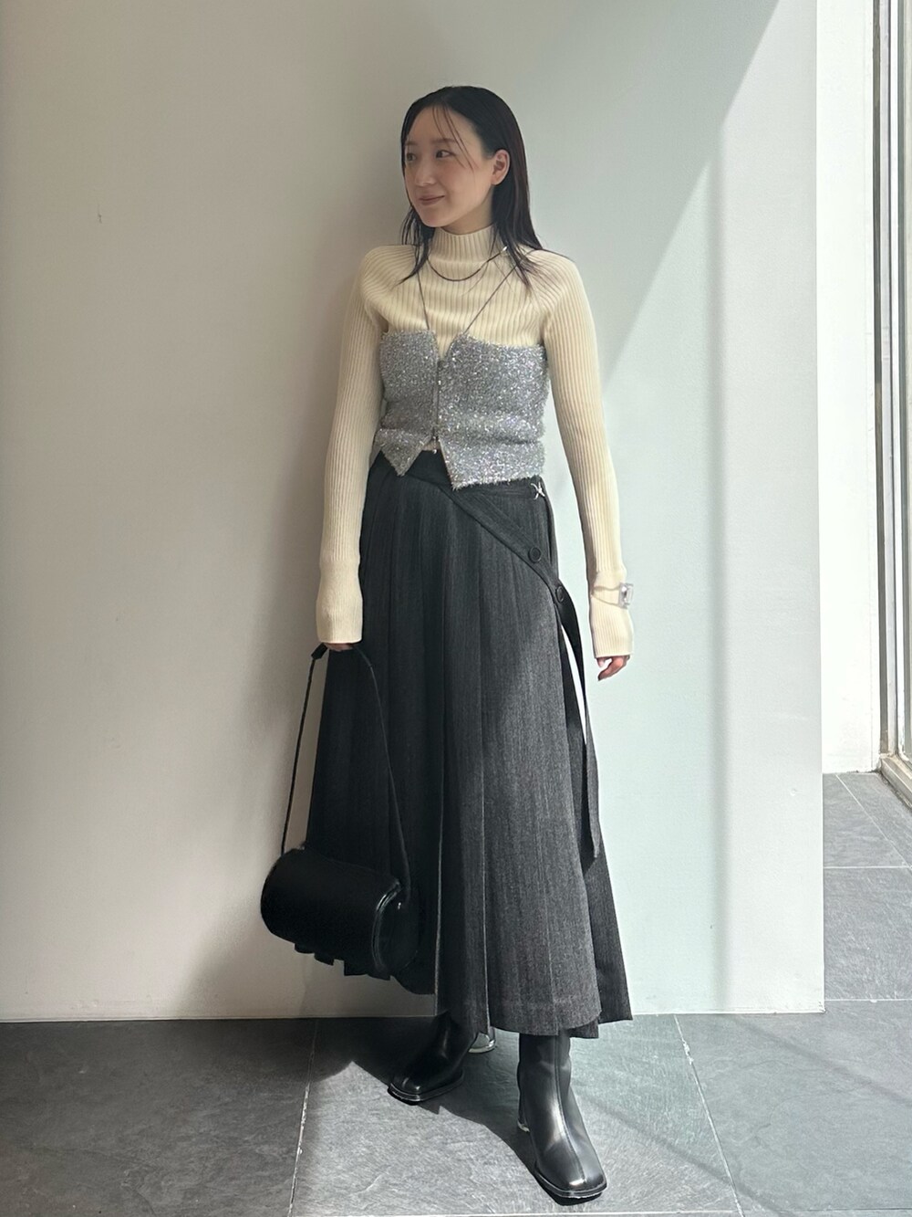 シルバー系のキャミソール、ホワイト系のニット/セーター、グレー系のスカートを着用したレディースの秋コーディネートの2枚目の写真